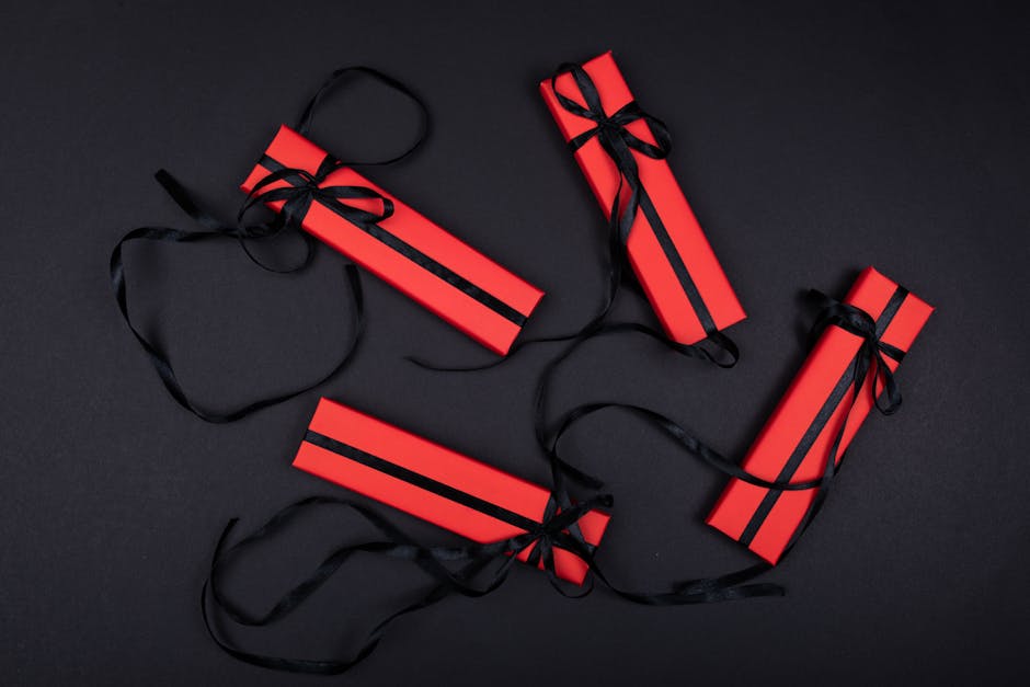 Four stylish red gift boxes tied with black ribbons on a black background.