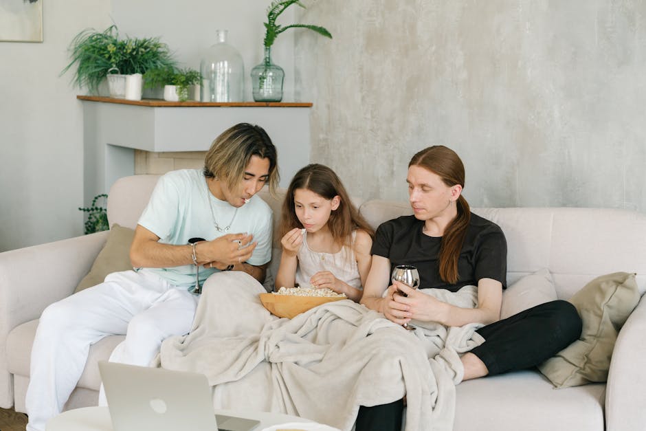 A family enjoying a movie and popcorn on the couch in a cozy living room setting.