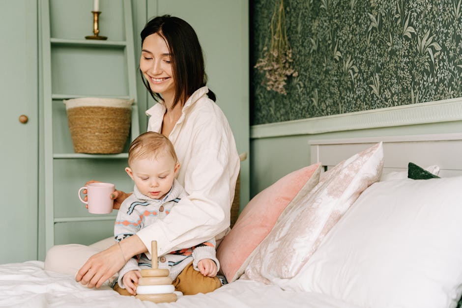 A mother enjoys quality time with her baby, playing with wooden toys on a bed in a cozy, decorated room.