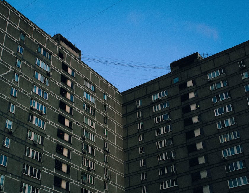 Low angle view of a concrete high-rise building with a clear blue sky above.