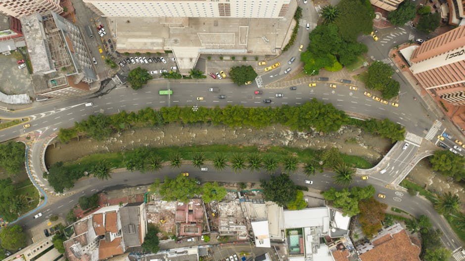 Aerial view showcasing a city's urban layout with roads, greenery, and palm trees.