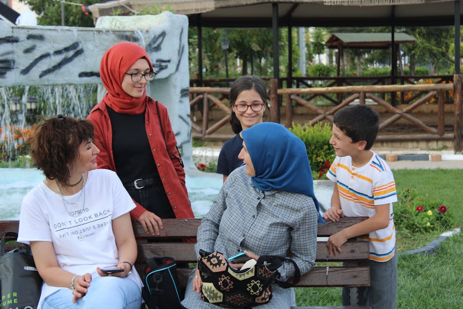 Three generations of a family sharing joyful moments on a park bench.