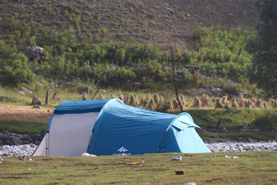 A blue tent pitched in a verdant, tranquil riverside setting, perfect for camping.