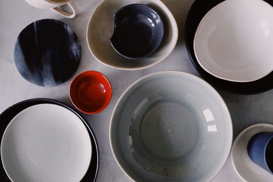 A collection of various colored ceramic bowls and plates, artistically arranged on a flat surface.