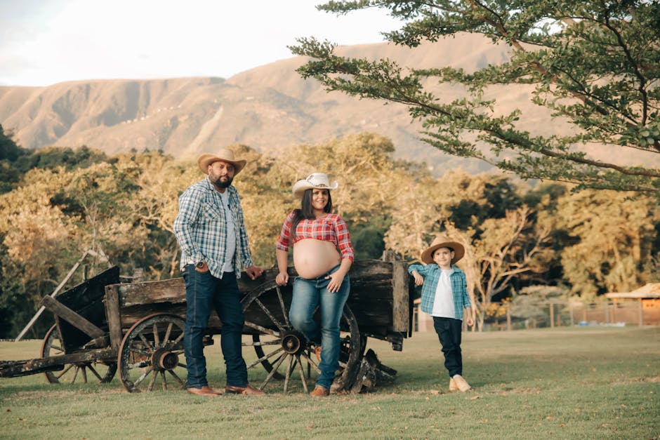 A cheerful family poses in cowboy hats on a rustic farm setting, capturing a joyful moment of togetherness.