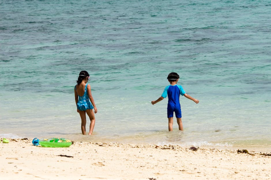Two children playing at the beach on a bright summer day, enjoying the ocean waves.