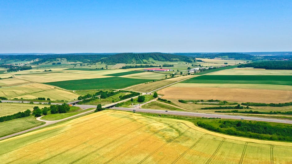 Aerial view of lush countryside fields in France during a bright summer day.