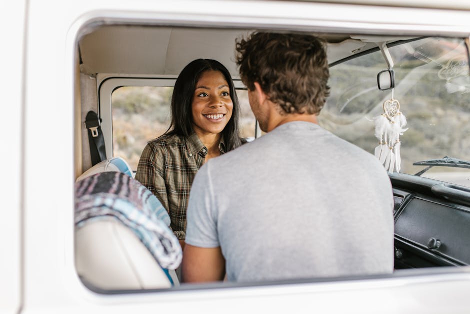 A smiling couple sits inside a van, creating joyful travel memories.