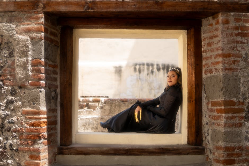 Woman in a stylish black dress seated in a historic window frame, Mexico City.