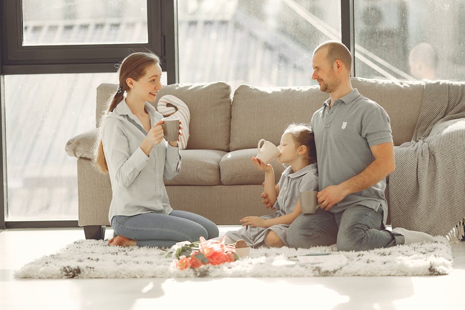 Cheerful family drinking tea in living room while having rest and laughing together during weekend while spending time and having fun