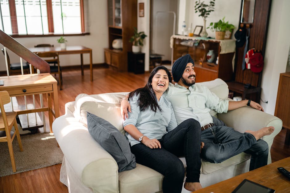 From above of young barefoot ethnic couple in casual outfit chilling together on comfortable sofa at cozy living room while having romantic weekend
