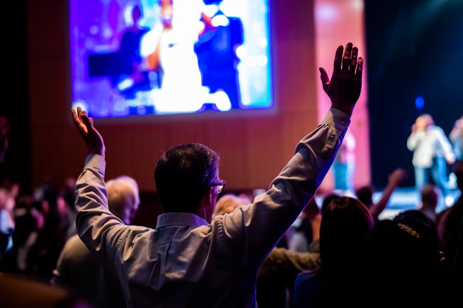 Audience member with raised hands enjoying a lively concert experience.