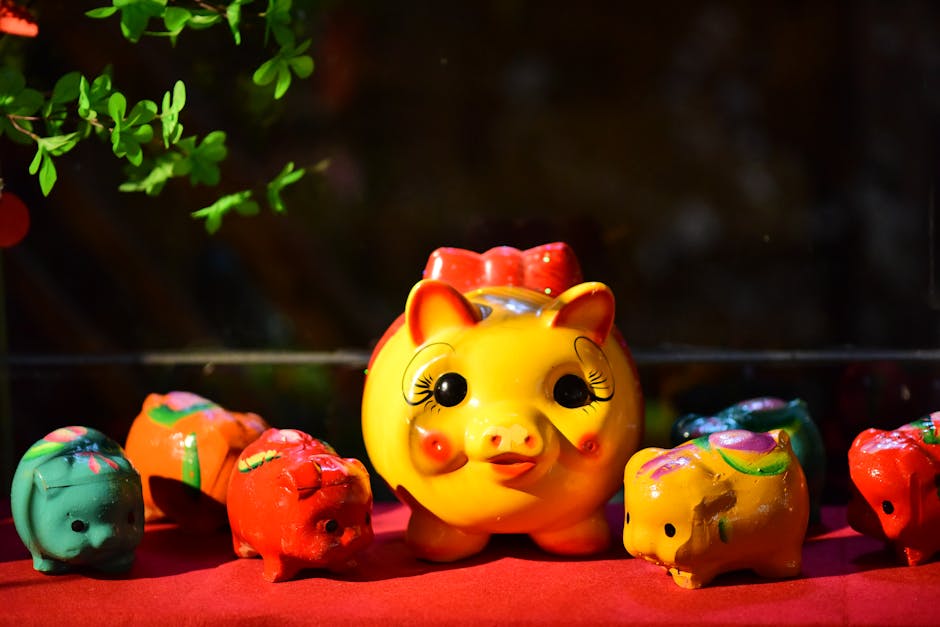 Brightly colored ceramic pigs on a red table with green foliage enhances festive look.