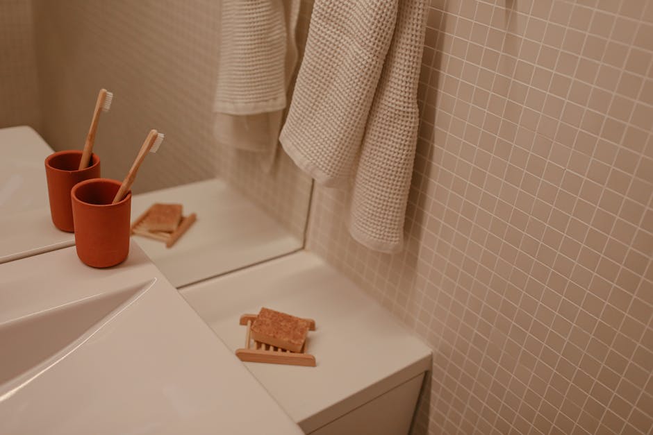 Modern minimalist bathroom scene with toothbrushes, towels, and soap.