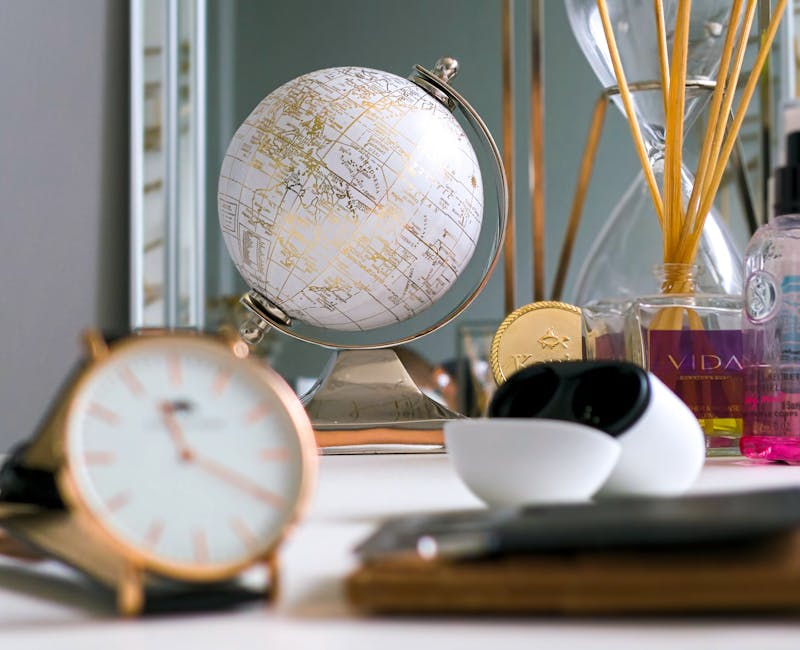 A stylish desk arrangement featuring a globe, clock, and various decorative items in a modern setting.