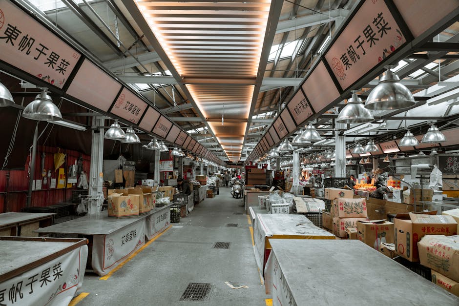An urban indoor market with empty stalls, showcasing overhead lights and Asian signage.