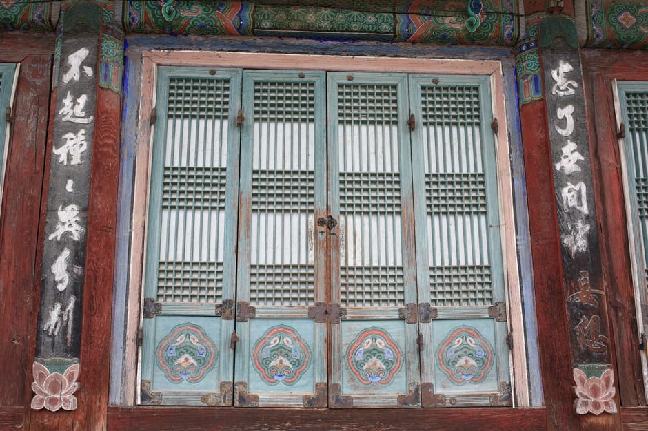 Close-up of a traditional Korean temple door in Seoul, showcasing intricate woodwork and vibrant colors.