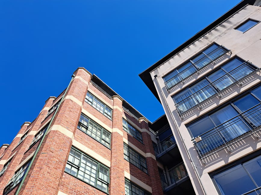 Stylish urban apartment buildings with balconies set against a clear blue sky, showcasing modern architecture.