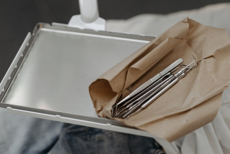 Close-up of dental tools wrapped in brown paper on a metal tray, highlighting dental care readiness.