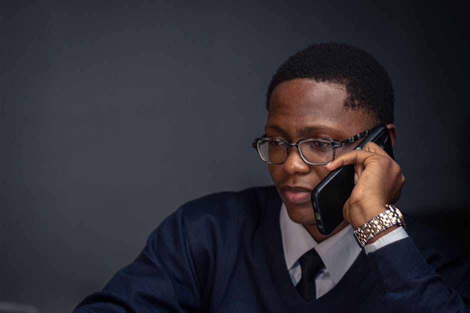 Businessman in suit talking on a mobile phone, focused and attentive in an office environment.