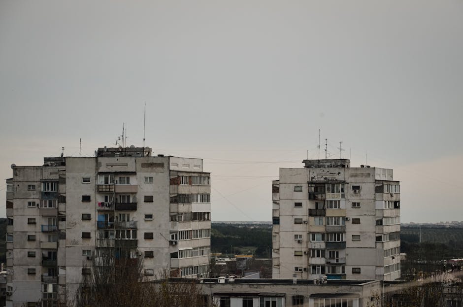 A pair of urban residential buildings under a grey, overcast sky, depicting city life.