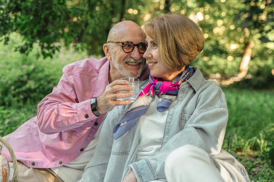 Happy senior couple sitting outdoors, enjoying a sunny day in the park, sharing affection and laughter.