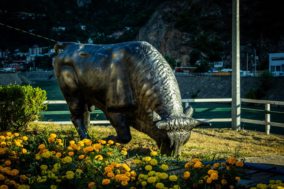 Striking bull statue amidst marigolds in Artvin, Türkiye, showcasing vibrant outdoor art.