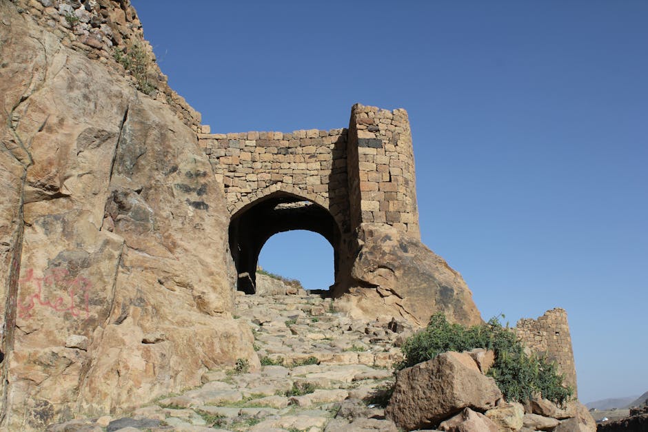Explore a historic stone gateway set amidst rocky terrain in a traditional Yemeni village.