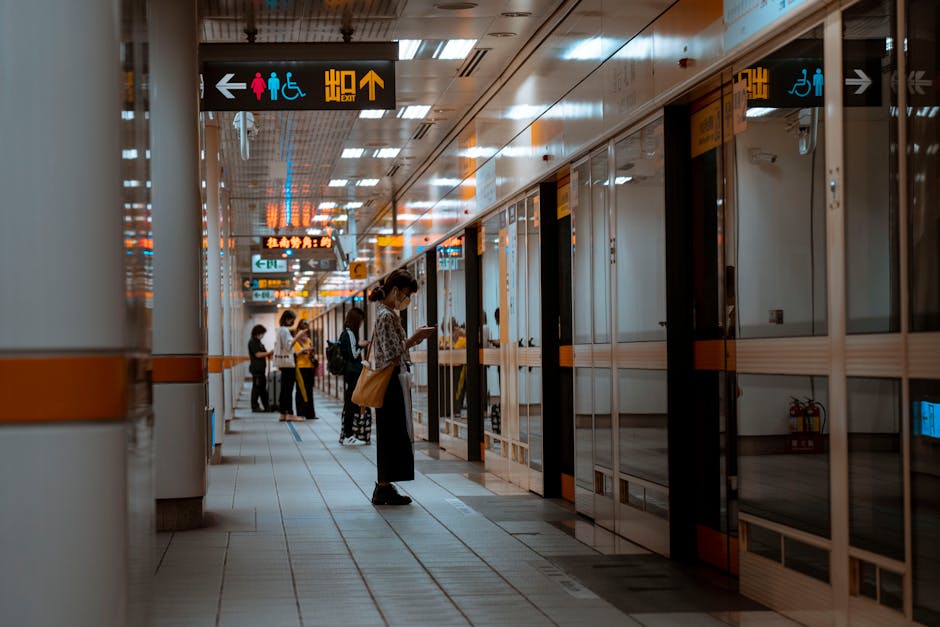 A bustling subway corridor with people standing and waiting near directional signs.