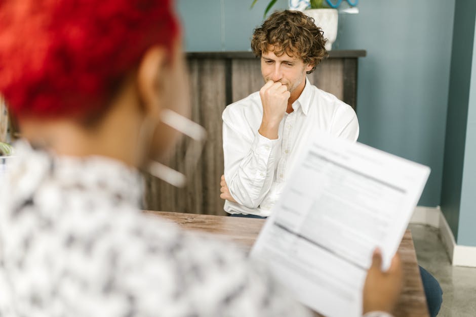 Man reflecting during a job interview in an office setting, highlighting thoughtfulness.
