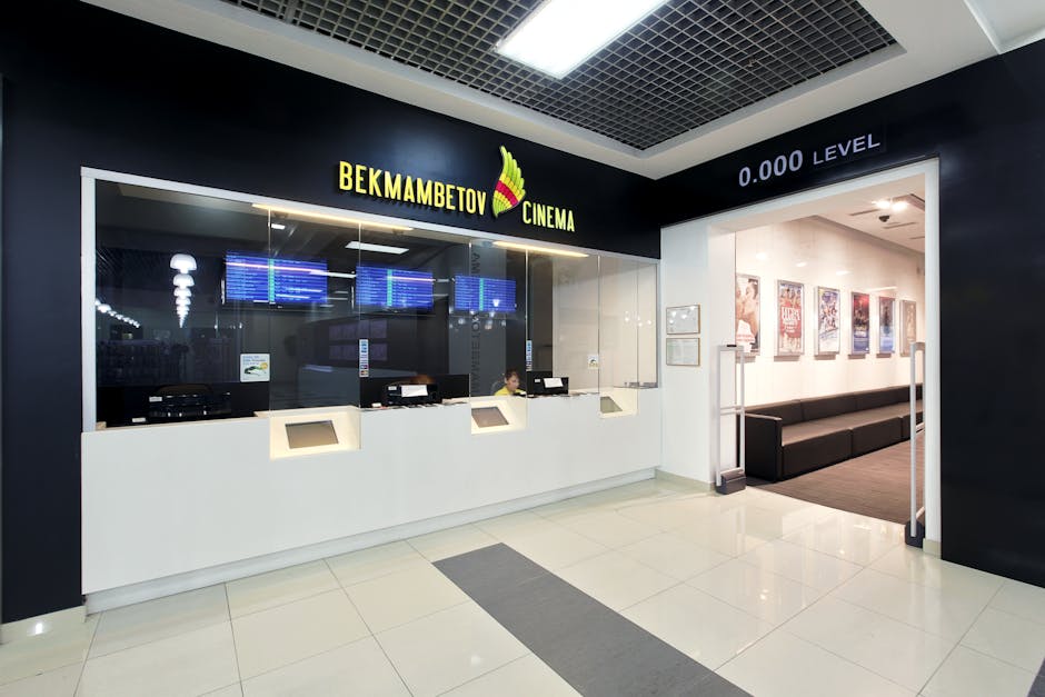 Interior view of a modern cinema box office with digital displays and sleek design, creating an inviting atmosphere.