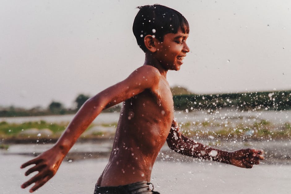 A happy child splashes joyfully in a rural outdoor setting, experiencing pure fun.