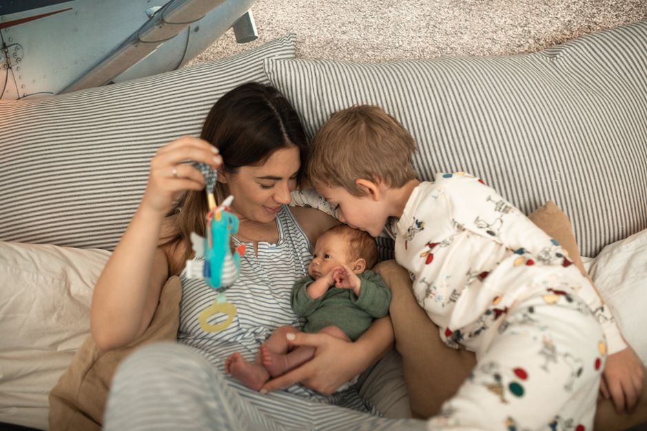 Mother with her newborn and son in a cozy setting, sharing affection.