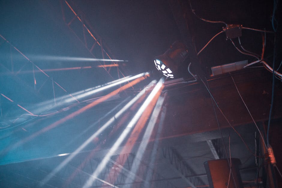 Illuminated light beams create dramatic effects against an industrial ceiling.