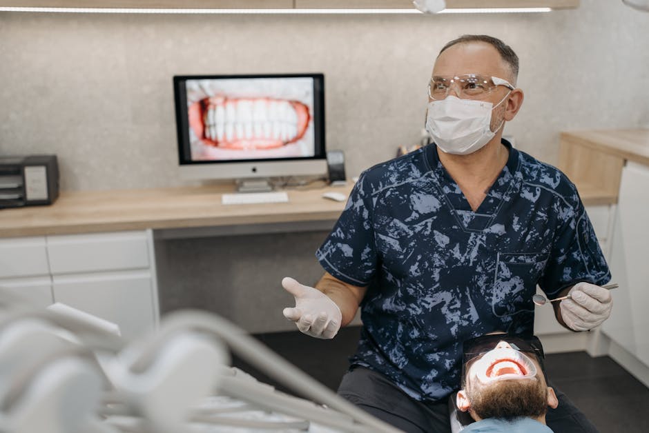 A dentist wearing a mask and gloves checks a patient's teeth in a modern dental clinic.