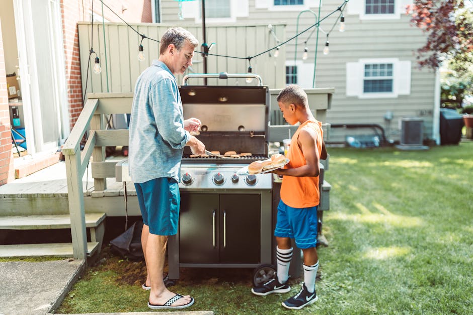 Father and son enjoying a summer barbecue in their backyard, bonding over cooking.
