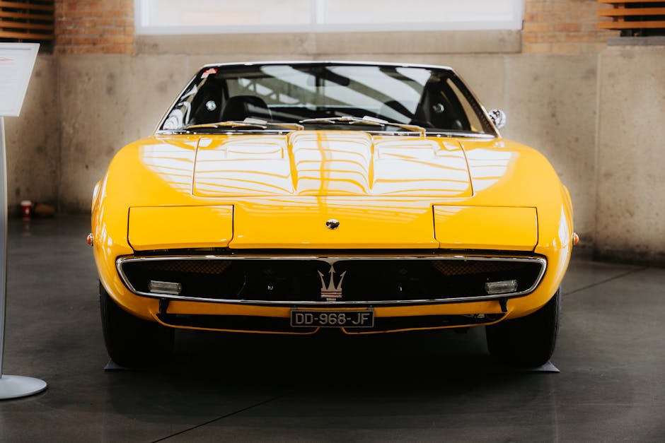 A classic yellow sports car showcased indoors, highlighting its sleek design and vintage appeal.