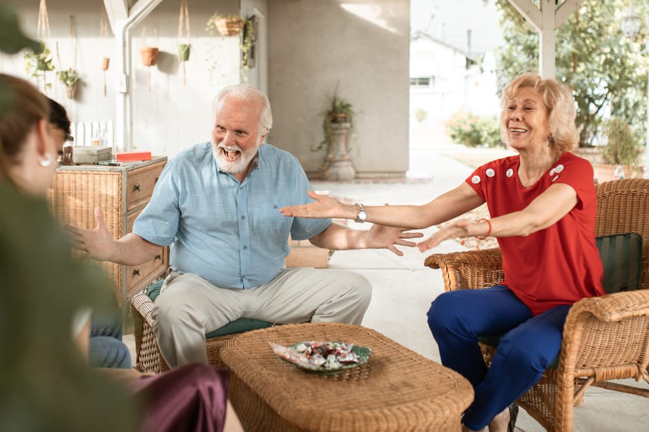 Happy senior couple having a lively chat on the patio with family.