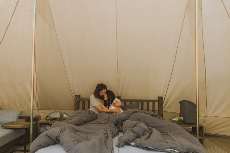 A couple enjoys a peaceful embrace inside a comfortable glamping tent, surrounded by nature.