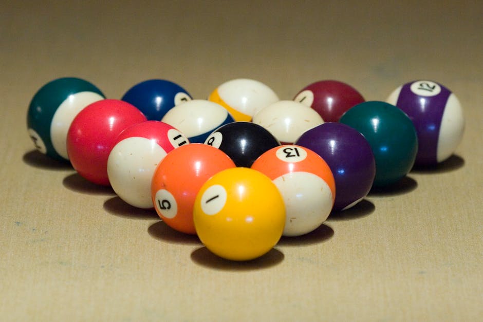 Vibrant billiard balls arranged in triangular formation on pool table.
