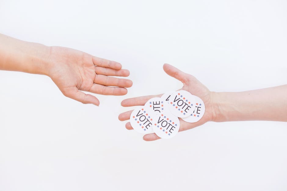 Close-up of hands exchanging vote stickers, symbolizing engagement in democratic election.
