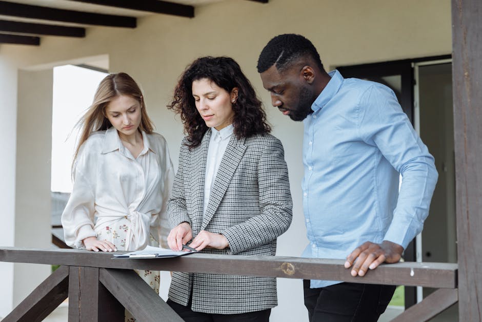 Three adults reviewing documents on a balcony during a real estate consultation.