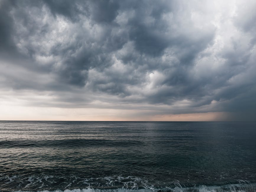 A stunning photo of dark storm clouds gathering over a calm ocean, creating a dramatic seascape.