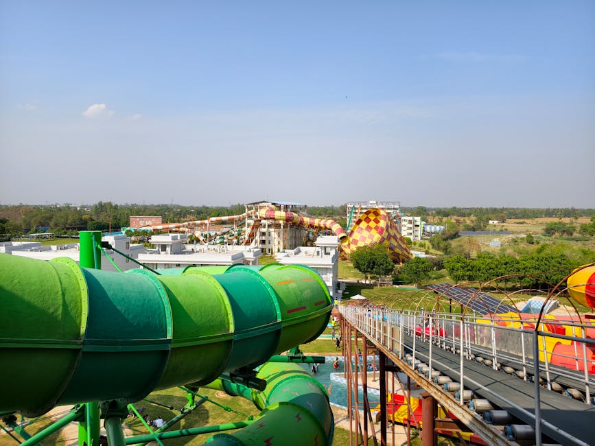 A vibrant outdoor water park with green slides and colorful attractions under a clear blue sky.