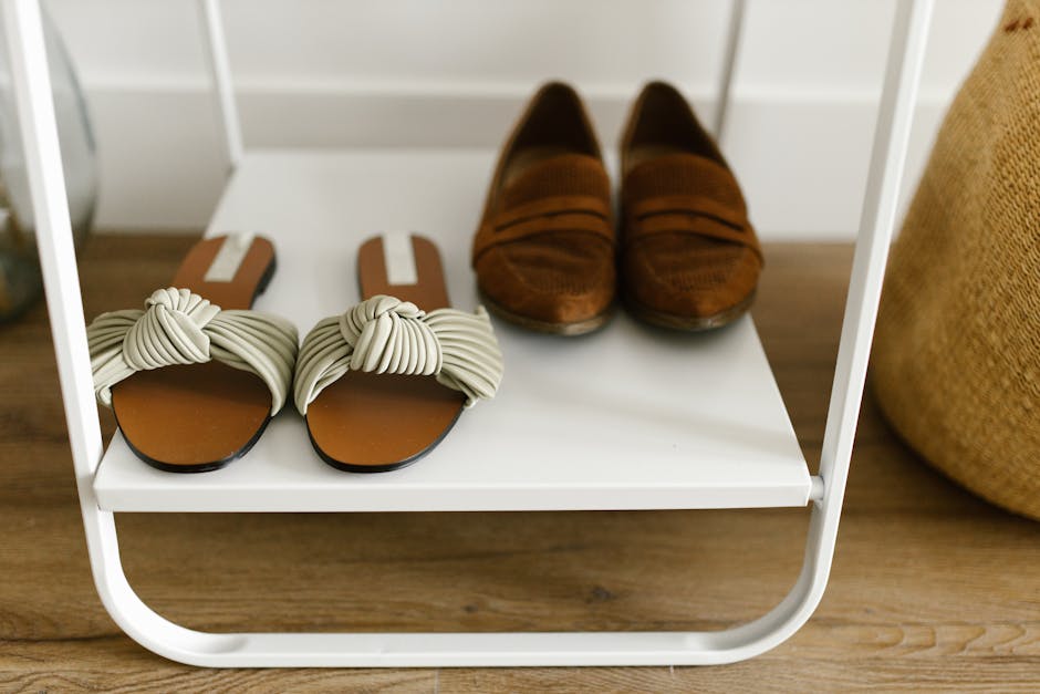Close-up of stylish sandals and loafers on a minimalist white shelf for fashion showcase.