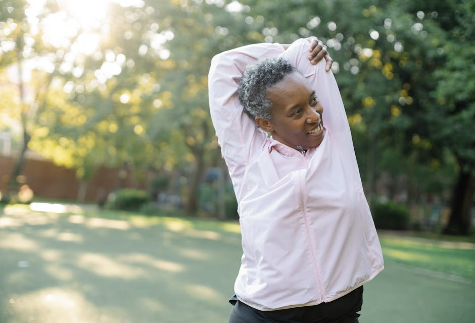 Elderly African American woman doing stretching exercises outdoors in a park, embracing a healthy lifestyle.