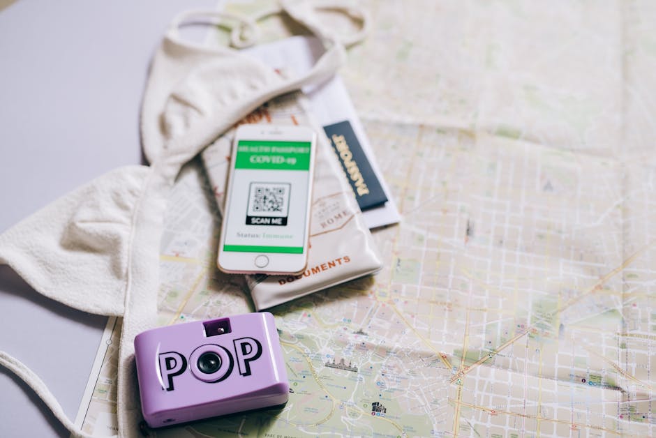 Flat lay of travel essentials including a passport, map, smartphone, and pop camera.