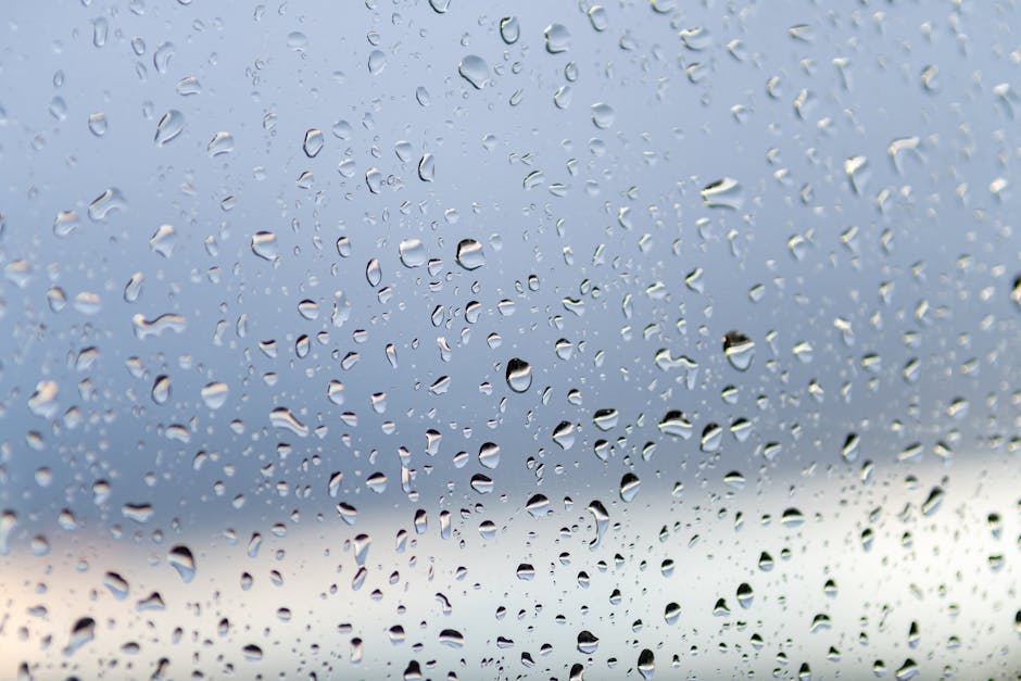 Close-up of raindrops on a window with a soft, blurred background creating a serene atmosphere.