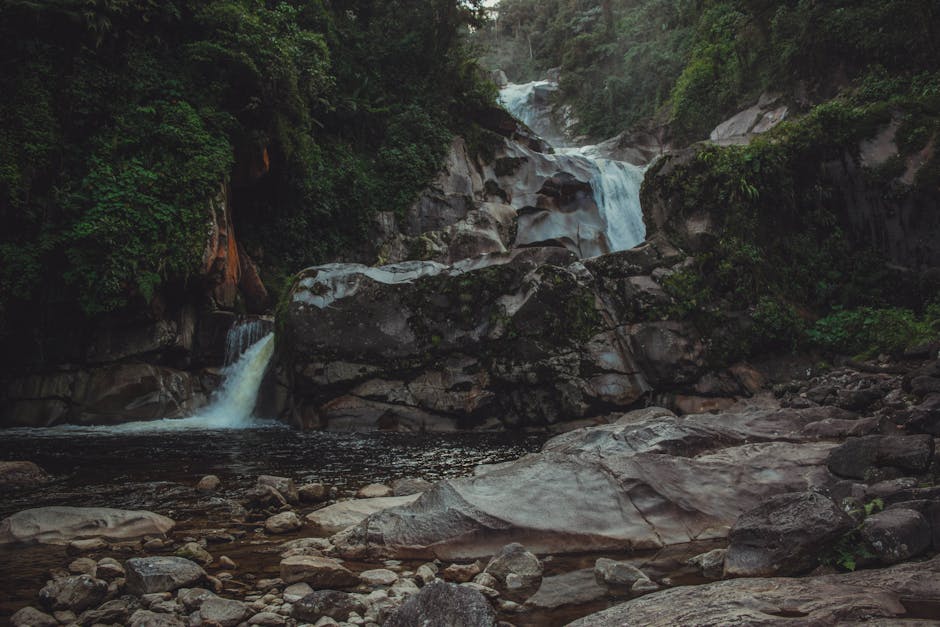 A magnificent waterfall cascading over rocks in a dense, green forest setting.