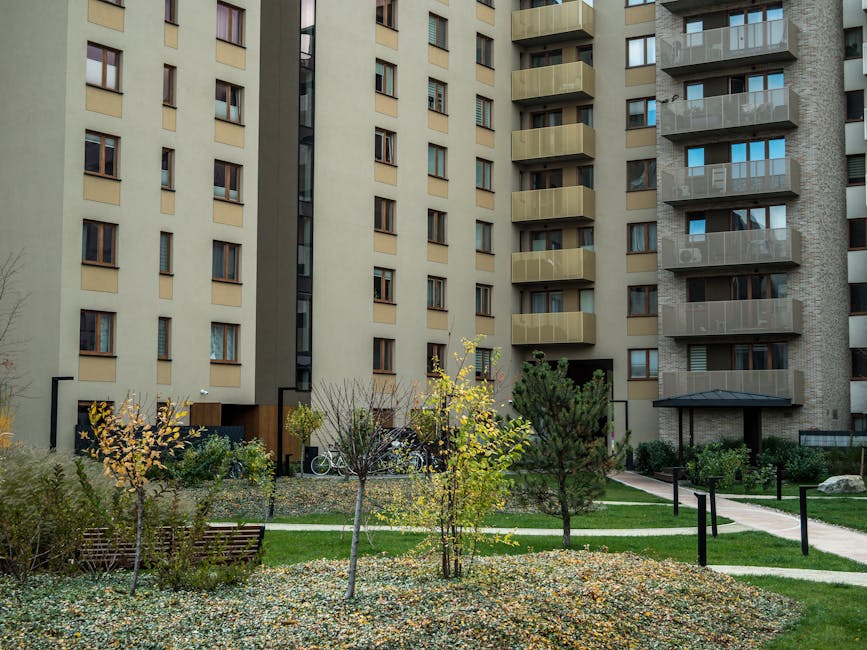 Contemporary high-rise apartment buildings with lush greenery and pathways in the courtyard.